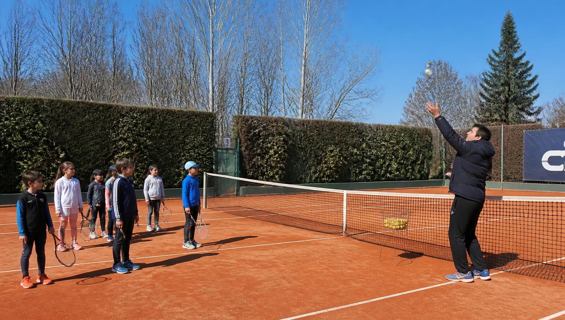 Kinderen krijgen tennisles op de gravelbanen van De Aeronauten